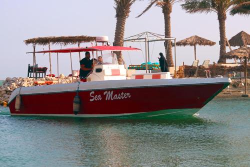 a red boat in the water next to a beach at Lagoona Beach Luxury Resort and Spa in Manama