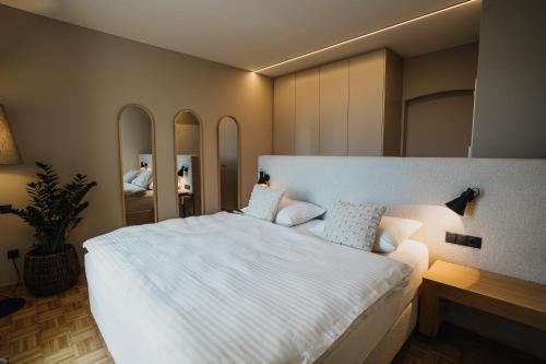 a bedroom with a large white bed and mirrors at meralino boutique apartment in Merano