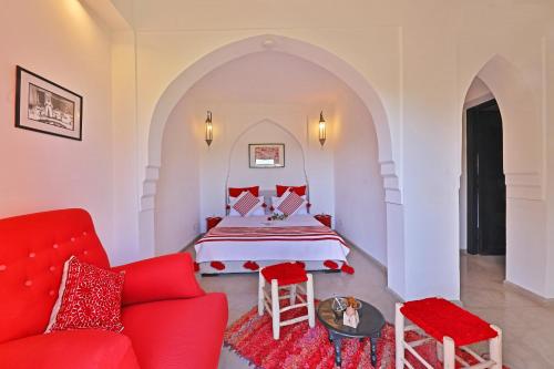 a bedroom with a bed and a red couch at DAR NOUJOUM in Marrakech