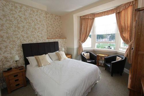 um quarto com uma cama, 2 cadeiras e uma janela em The Warwick em Weymouth