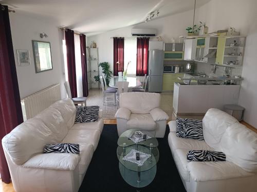 una sala de estar con 2 sofás blancos y una mesa. en Apartment Jagoda, en Primošten