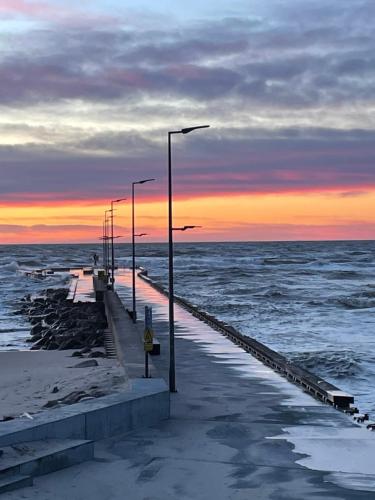 a pier with street lights and the ocean at sunset at Hotel VANDret in Løkken