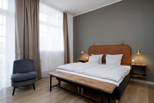 a bedroom with a bed and a blue chair at Hotel VANDret in Løkken
