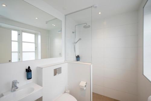 a bathroom with a shower and a toilet and a sink at Hotel VANDret in Løkken
