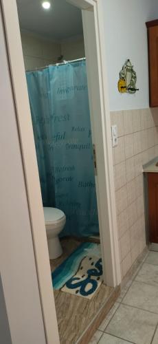 a bathroom with a toilet with a blue shower curtain at Ilio Socrates in Skala Marion