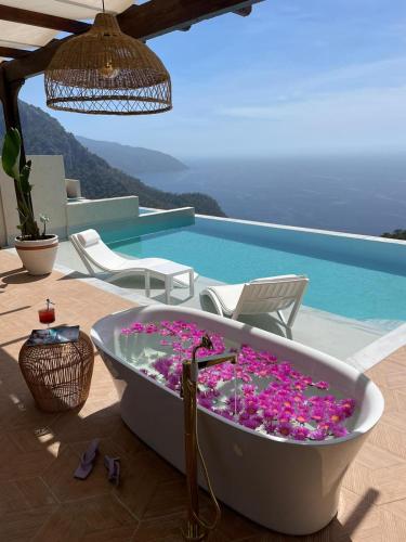 a bath tub filled with purple flowers next to a pool at Lissiya Hotel in Faralya
