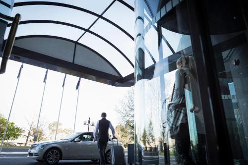 a man standing next to a car in front of a store at Mercure Melbourne Albert Park in Melbourne