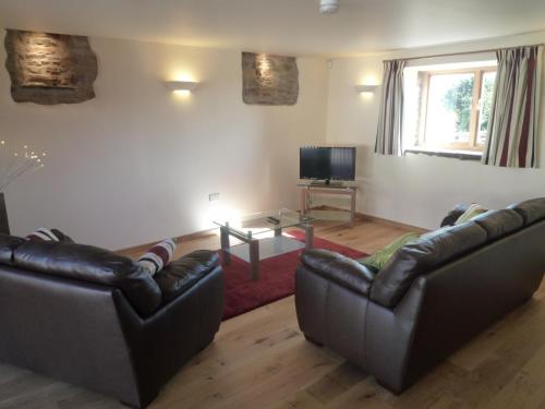 a living room with two leather couches and a television at The Barn at Freemans Farm in Alveston