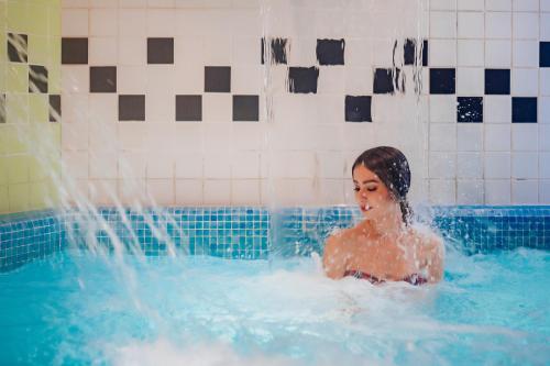 a woman in a swimming pool with water coming out at Gran Hotel Don Manuel in Cáceres