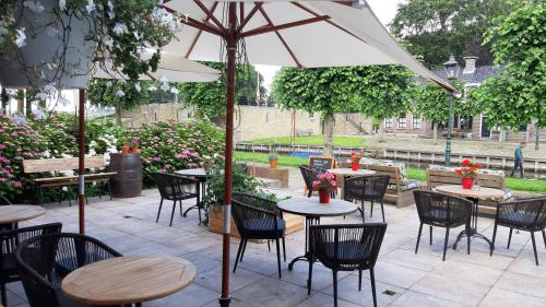 a patio with tables and chairs and an umbrella at Hotel Stedswal in Sloten