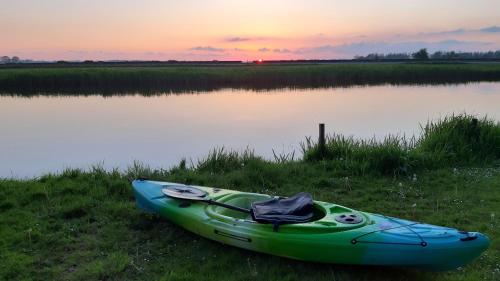 a green kayak sitting on the side of a lake at Hotel Stedswal in Sloten