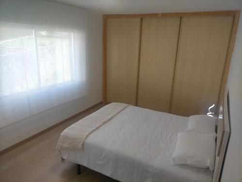 a small bedroom with a bed and a window at Alojamiento Costas Bueu in Bueu