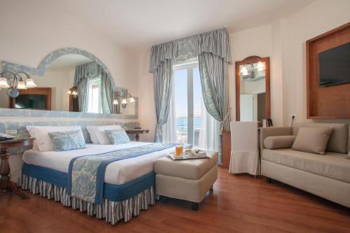 a bedroom with a large bed and a couch at Hotel Cavalieri Palace & Suites in Lido di Jesolo