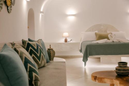 a white bedroom with a bed and a table at Sun Angelos Oia - Luxury Cave Suites in Oia
