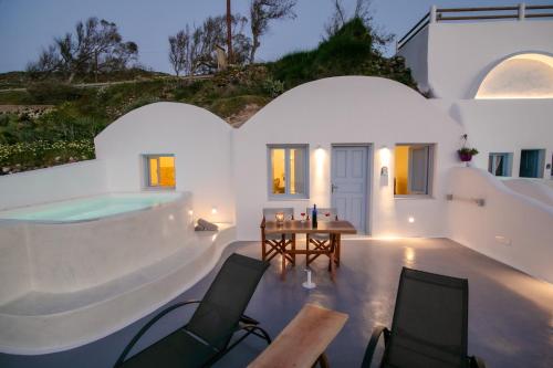 a home with a pool and a table and chairs at Sun Angelos Oia - Luxury Cave Suites in Oia