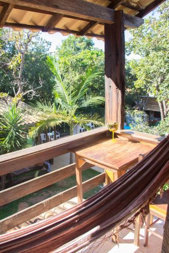 a hammock on a porch with a table and trees at Vila Flores Pousada in Serra do Cipo