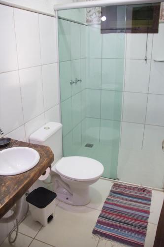 a bathroom with a toilet and a glass shower at Vila Flores Pousada in Serra do Cipo