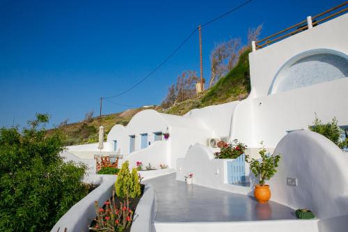 a view of a white building with plants at Sun Angelos Oia - Luxury Cave Suites in Oia