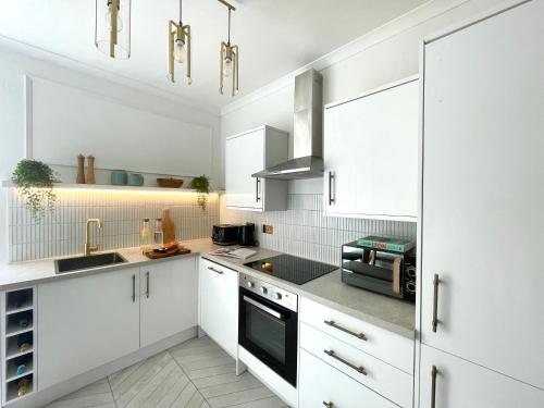 una cocina blanca con armarios y electrodomésticos blancos en Stylish & Chic Central Apartment with Hot Tub en Perth