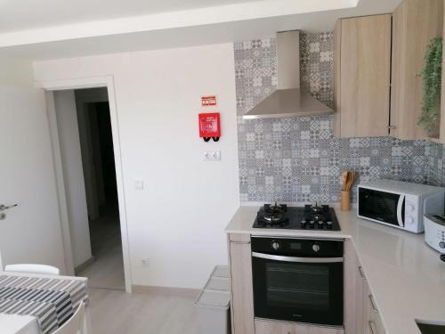 a kitchen with a stove and a microwave at Baleal Atlantic View House in Baleal