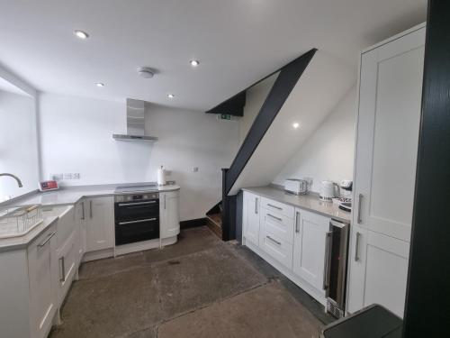 a kitchen with white cabinets and a staircase at Luxurious Cottage with hot tub, Lake District in Duddon