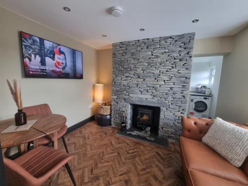a living room with a stone fireplace and a table at Luxurious Cottage with hot tub, Lake District in Duddon