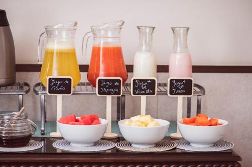 een plank met vier flessen sap en fruitschalen bij Hostal Lirium in Arequipa