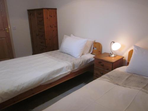 a bedroom with two beds and a lamp on a night stand at Easter Bowhouse Farm Cottage in Linlithgow