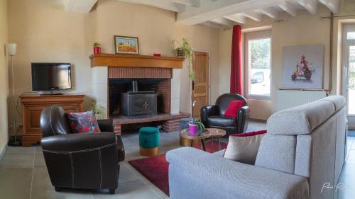 a living room with a couch and a fireplace at Gîte La Pironnière - Piscine, Nature, au bord de la Rivière in Montreuil-sur-Maine
