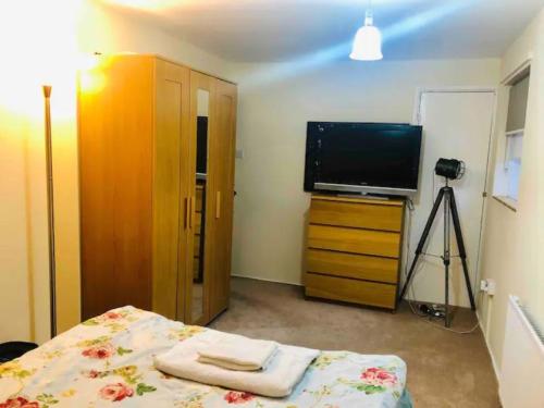 una camera con letto, televisore e cassettiera di Private room 4-5 minutes drive to Luton Airport a Luton