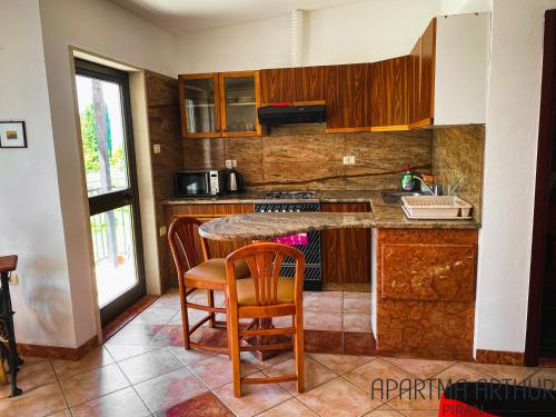 una cocina con armarios de madera, mesa y sillas en Aparment Arthur en Piran