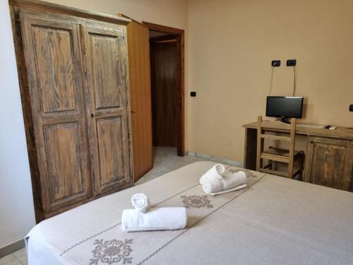 a bedroom with two towels on a bed with a television at Hotel Plammas in Santa Maria Navarrese