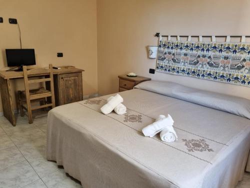 a bedroom with two beds and a desk and a television at Hotel Plammas in Santa Maria Navarrese