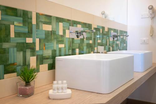 a bathroom with a white sink and a green tile wall at B&B Agramonte in Ispica