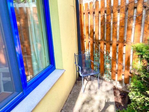 einem Stuhl, der vor einem Fenster neben einem Zaun sitzt in der Unterkunft Blumental Apartment II in Wien