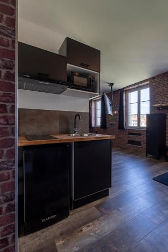 - une cuisine avec des placards noirs et un évier dans l'établissement Le New-York Spa, à Saint-Étienne