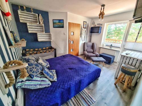 a bedroom with a blue bed and a chair at A morze! Agroturystyka Nowy Kraków pod Darłowem in Jeżyce