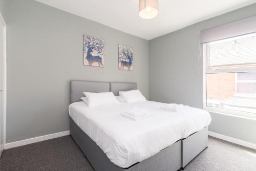 a bedroom with a bed with white sheets and a window at Thurgarton House - Cosy and Calm 2bed in Nottingham