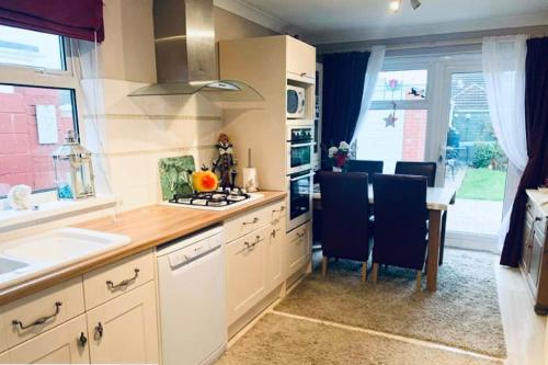 a kitchen with a sink and a table with chairs at Rosewood Guest House in Swindon