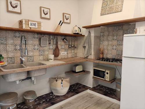 a kitchen with a sink and a white refrigerator at Amelia Apts & Rooms in Alghero