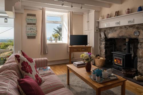 a living room with a couch and a fireplace at Arallt Holiday Cottage in Llithfaen