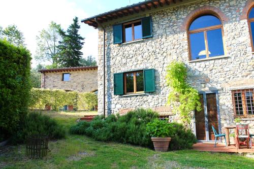 Casa de piedra con ventanas verdes y patio en Qui Con Te, en Paterno