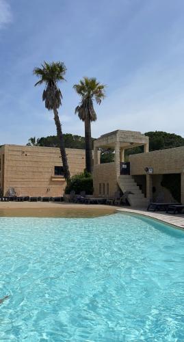 a swimming pool in front of a building with palm trees at Camping les Cigales - Mobil-home 4/6 personnes in Le Muy
