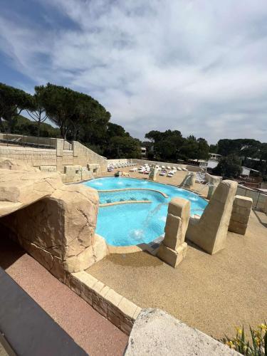a swimming pool in a resort with a rock wall at Camping les Cigales - Mobil-home 4/6 personnes in Le Muy