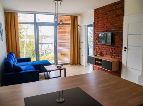 ein Wohnzimmer mit einem blauen Sofa und einer Ziegelwand in der Unterkunft Nowoczesny Apartament z widokiem na jezioro in Charzykowy