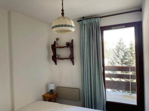 a bedroom with a bed and a window and a lamp at ORCIERES APPARTEMENT 6 PERSONNES AVEC PARKING in Orcières
