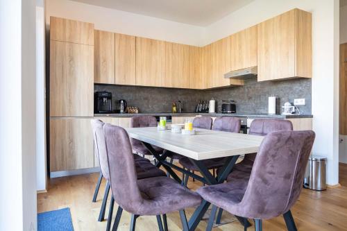 a kitchen with a table and purple chairs at Luxury Apartment Monte Carlo in Pörtschach am Wörthersee