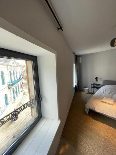 Un dormitorio con una gran ventana y una cama. en Laboutique2, en Lormes