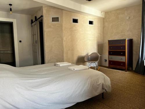 - une chambre avec un grand lit blanc et une commode dans l'établissement Laboutique2, à Lormes