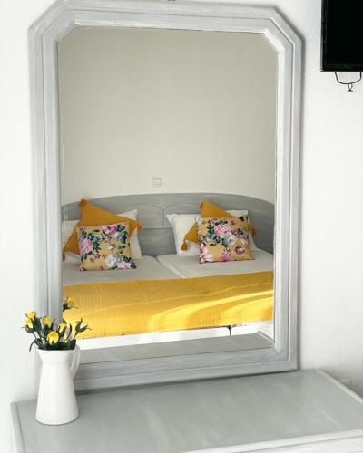 una camera con specchio che riflette un letto con cuscini; di ALEKA KOTSI ROOMS 2 a Igoumenítsa